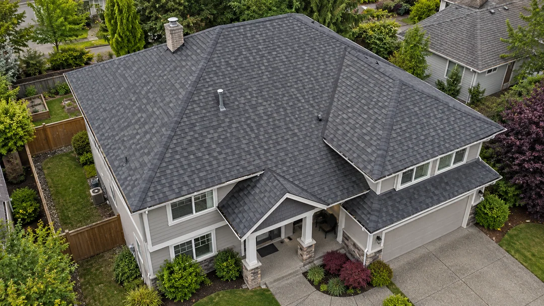 Aerial view of a two-story house with architectural asphalt shingles, showing its hip roof, valleys, gutters and roof openings.